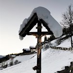 Schneebedecktes Flurkreuz am Wegesrand