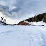 Inmitten schneebedeckter Wiesen liegt die Geisleralm