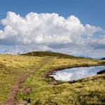 Die gegenüberliegenden Dolomiten bilden einen reizvollen Kontrast zu den sanften Almwiesen