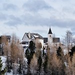 Die Wallfahrtskirche Heilig Kreuz wird von Lärchen umstanden