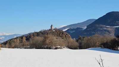 Die St. Verena Kirche thront auf einem bewaldeten Porphyrhügel