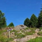 Hinter dem Gipfelkreuz des Scheibenbergs führt der Weg zur Zirmaitalm weiter