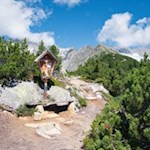 Bei der kreuzgeschmückten Sitzbank erhascht man erstmals einen Blick auf den Kreuzkofel