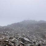 Zwischen den Nebelschleiern taucht das Gipfelkreuz der Wilden Kreuzspitze auf