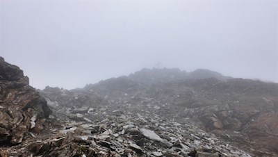 Zwischen den Nebelschleiern taucht das Gipfelkreuz der Wilden Kreuzspitze auf