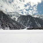 Der Antholzer See wird von dunklen Wäldern und majestätischen Gipfeln umrahmt