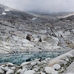 Eiskaltes Gletscherwasser fließt über die glatt geschliffenen Felswände in den Gletschersee