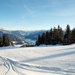 Blick ins winterlich verschneite Tal und auf die umliegende Bergwelt
