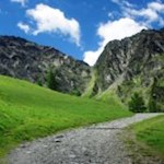 Blühende Almwiesen und mächtige Felsen umsäumen den Weg zum Klaussee